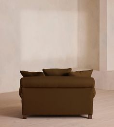 a brown couch sitting on top of a hard wood floor next to a white wall