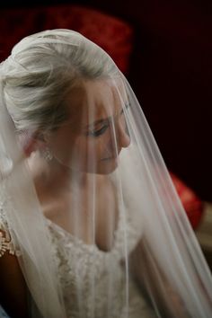 a woman in a wedding dress looking down at her veil