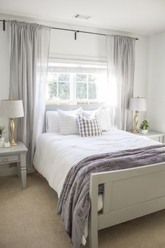 a white bed sitting under a window in a bedroom