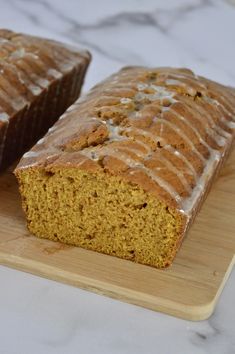 two slices of pumpkin bread with icing on a cutting board next to each other