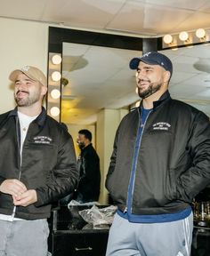 two men standing next to each other in front of a mirror