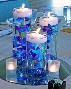 blue flowers and candles in glass vases on a table