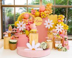 a pink and yellow birthday party with balloons, flowers, and cake on the table