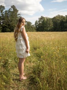 This eyelet ruffled mini dress displays an upper chest drawstring, bow detail, self-tie ribbon straps, and ruffled edge layers. The model is wearing a size small Ruffled Tie Straps Mini Dress For Garden Party, Garden Party Mini Dress With Ruffled Tie Straps, Tiered Lace Trim Mini Dress For Garden Party, Summer Tiered Ruffle Dress With Lace Trim, Daywear Ruffle Dress With Ruffled Hem And Straps, Ruffle Dress With Ruffled Straps For Daywear, Spring Mini Dress With Lace Trim And Tiered Skirt, White Tiered Dress With Ruffled Straps, Tiered Dress With Tie Straps For Day Out