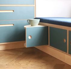 a blue bench with drawers and a cup on it in a room that has wood floors