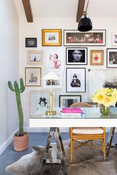 a room with pictures on the wall and a table in front of a cactus plant