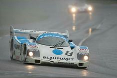 a race car driving down the road in the rain