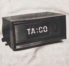 an alarm clock sitting on top of a white sheet with the word taco printed on it