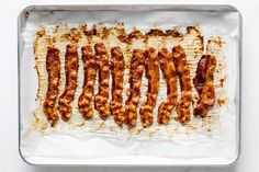 bacon strips are lined up on a baking sheet