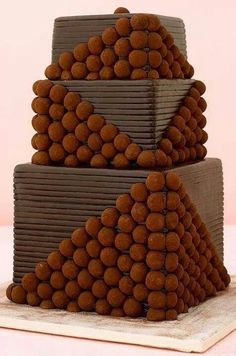 a three tiered cake with chocolate frosting and lots of balls on the top