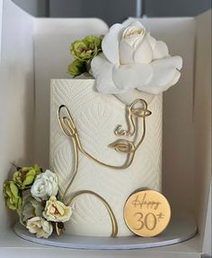 there is a white cake with flowers on the top and a gold sign that says happy 30th