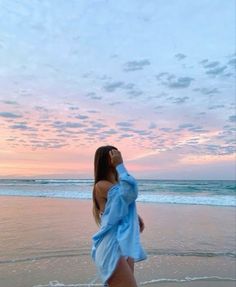 a woman standing on top of a beach next to the ocean