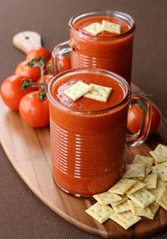 two glasses of tomato soup with crackers and tomatoes