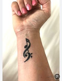 a woman's arm with a musical note tattoo on the left side of her wrist