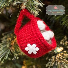 a red ornament hanging from a christmas tree with snowflakes on it