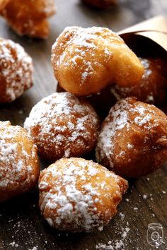 powdered sugar covered donuts sitting on top of a wooden table