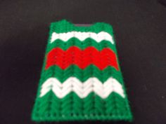 a green, white and red knitted case sitting on top of a black surface