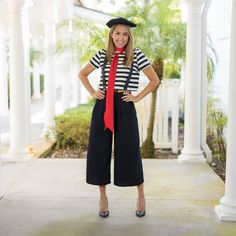 a woman in black and white striped shirt with red tie posing for the camera while wearing wide legged culots