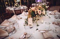 the table is set with wine glasses, plates and flowers in vases on it