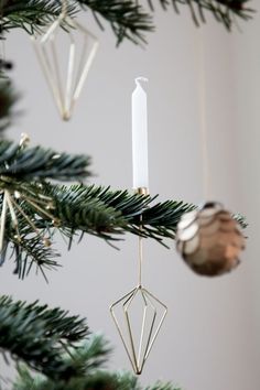 an ornament hanging from a christmas tree next to a candle and some ornaments