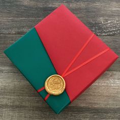 a red and green box with a gold seal on the lid sitting on a wooden table