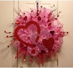 a pink and red heart wreath hanging on the front door to someone's house