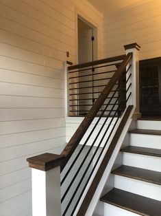 the stairs are made of wood and have metal railings on each handrail, along with white painted walls