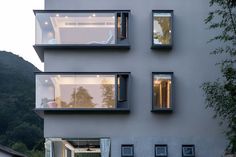 three windows on the side of a building with mountains in the backgrouds