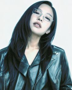 a woman with long black hair wearing glasses and a leather jacket is posing for the camera