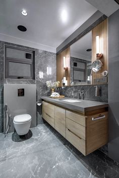 a modern bathroom with marble counter tops and wooden cabinets, along with a white toilet