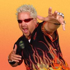 a man with white hair wearing sunglasses and pointing to the side in front of an orange background