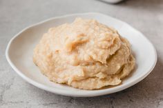 a white plate topped with mashed potatoes on top of a gray countertop next to a bottle