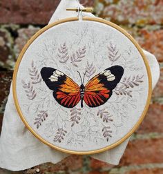 an embroidered butterfly is hanging on a brick wall