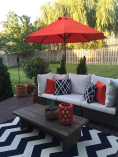 a couch and coffee table on a patio with an umbrella