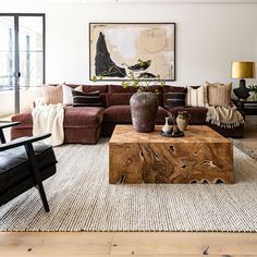 a living room filled with furniture and a large painting on the wall above it's coffee table