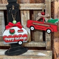 two christmas ornaments hanging from a wooden fence with the words happy holidays written on them