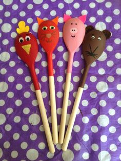 four wooden spoons with animal faces on them sitting on a purple and white polka dot tablecloth