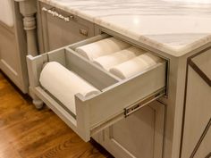 an open drawer in the middle of a kitchen counter with two rolls of toilet paper