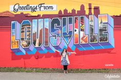 a woman standing in front of a colorful wall with the word nashville painted on it