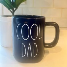 a coffee mug with the words cool dad written on it next to a potted plant