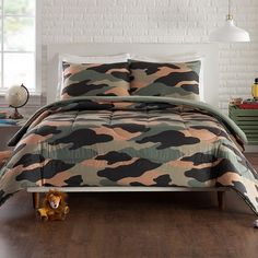 a camo comforter set in a bedroom with a toy dog on the floor