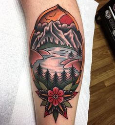 a person with a tattoo on their arm that has mountains and trees in the background