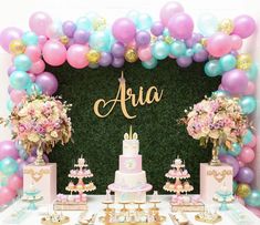 a table topped with cake and balloons next to a sign that says aria on it