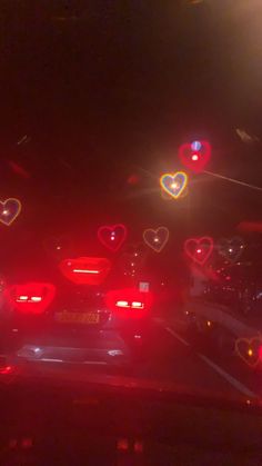 many cars are driving down the street at night with heart shaped lights in the dark