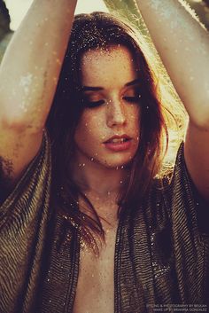 a woman with her hands on her head in the air and water droplets all over her face