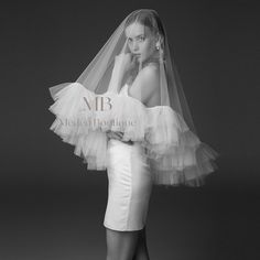 black and white photograph of woman in wedding dress with veil over her head, posing for the camera