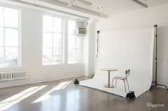 an empty room with two chairs and a table in front of a white backdrop on the floor