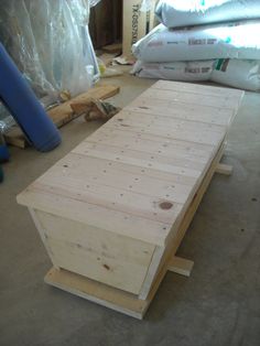 a wooden bench sitting on top of a floor next to some bags and other items