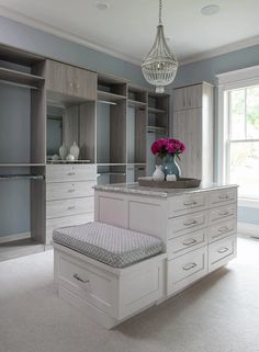 a large walk in closet filled with lots of white drawers and cabinets next to a chandelier