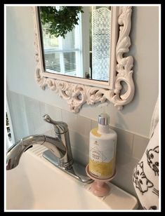 a bathroom sink with a soap dispenser next to it and a mirror on the wall